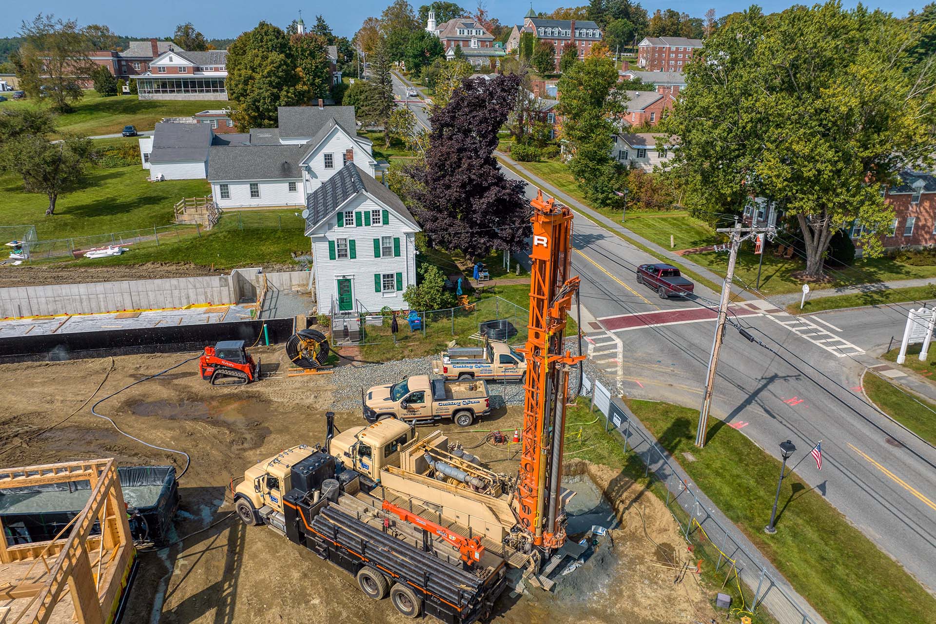 geothermal construction site with various trucks and orange drilling rig
