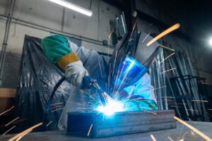 sparks flying while person in helmet welds