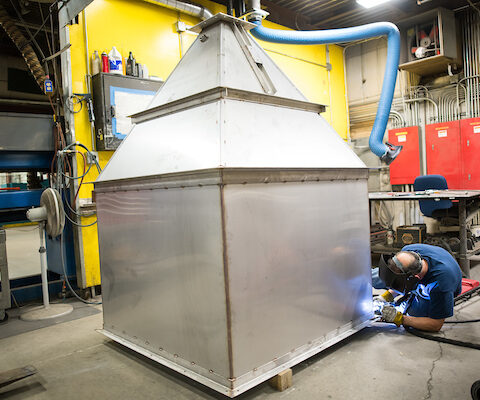 NE Air employee laying on ground to work on large coffee bean hopper
