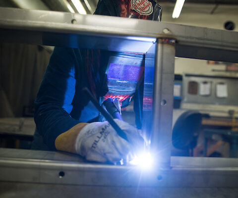 Employee wearing a welding helmet and gloves while welding