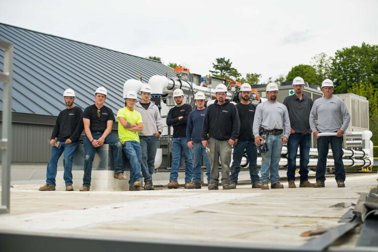 group of NE employees wearing hardhats on a rooftop